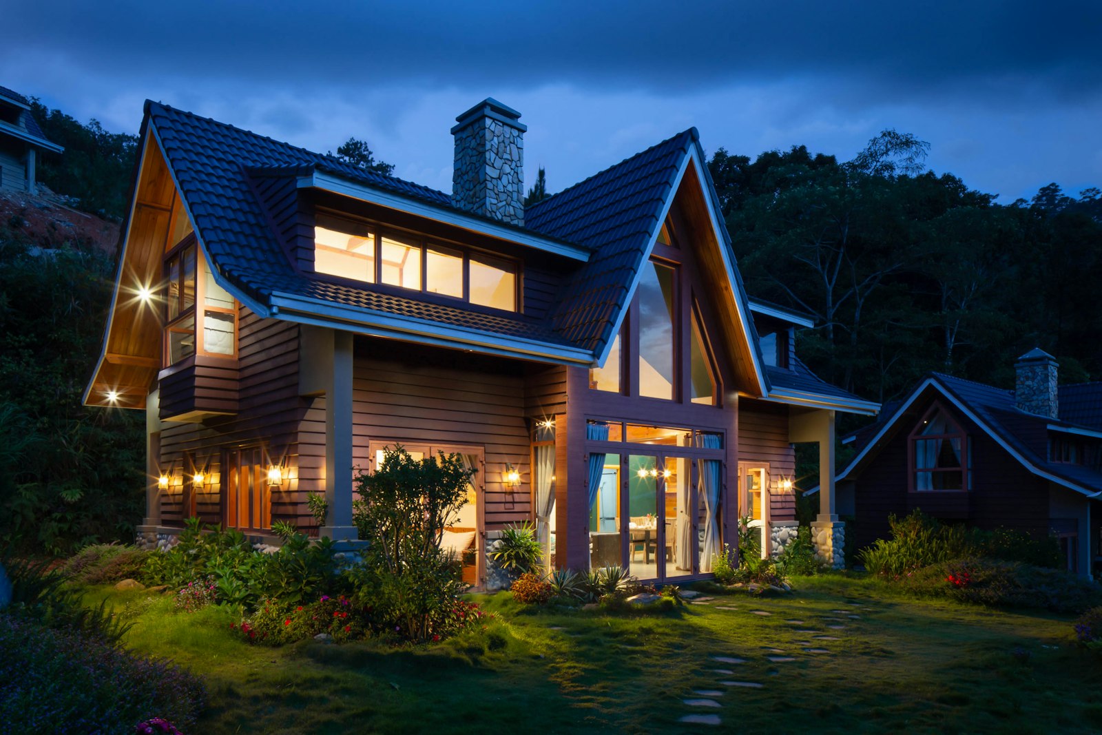 Landscaped home lit at dusk with stone walkway